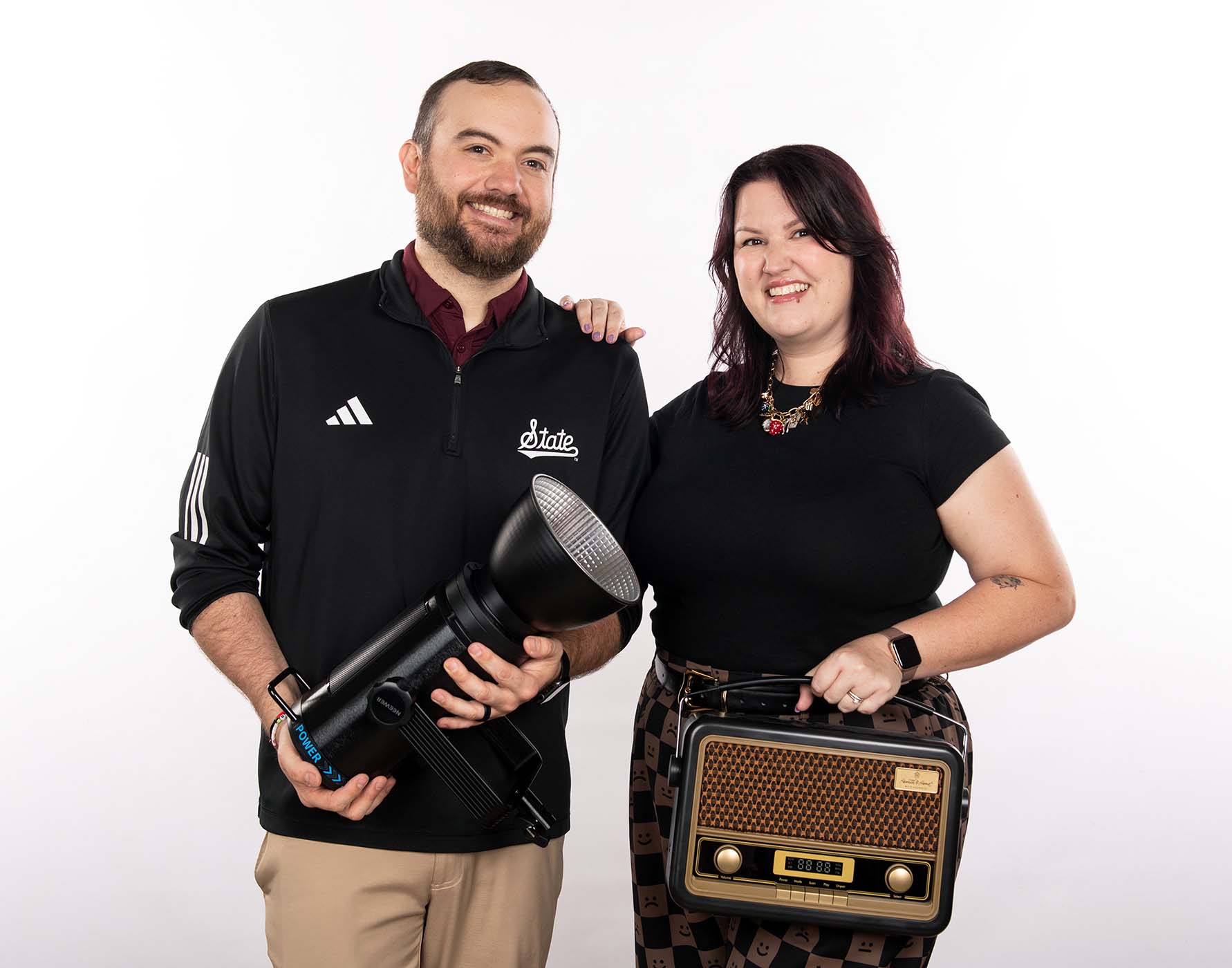 Greg Thorn, a Mississippi State lighting designer, and Becca Thorn, general manager of the university's radio station, posing with a studio light and a vintage radio