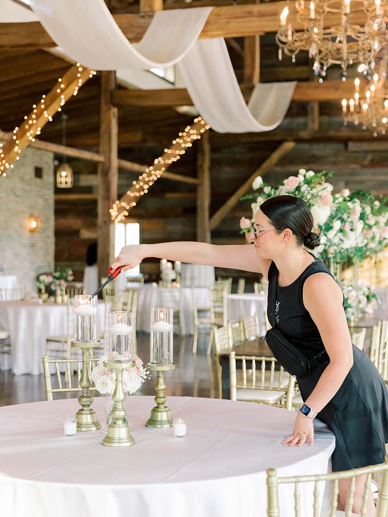 Olivia Miley lighting candles on a table set for a wedding reception