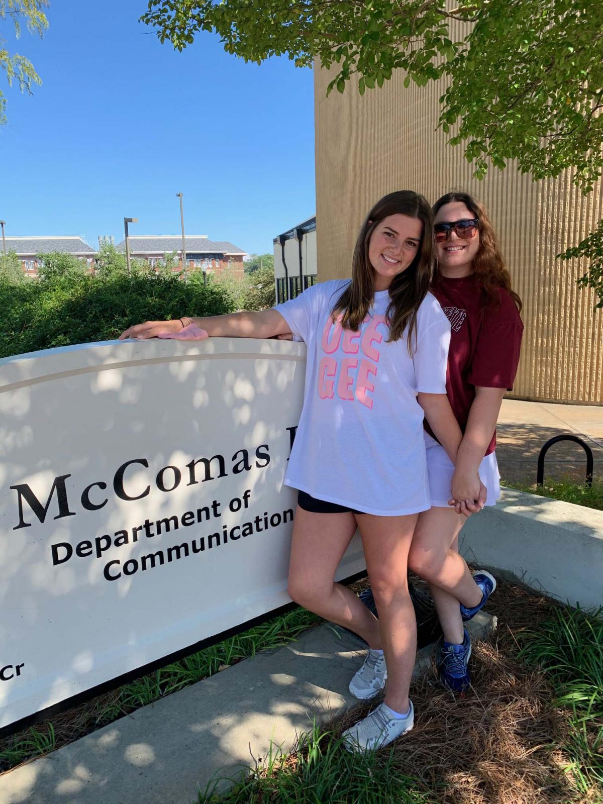 Students standing by McComas Hall sign