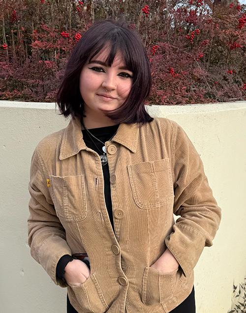 Photo of Erin Erter with hands in pocket standing outside McComas Hall at MSU